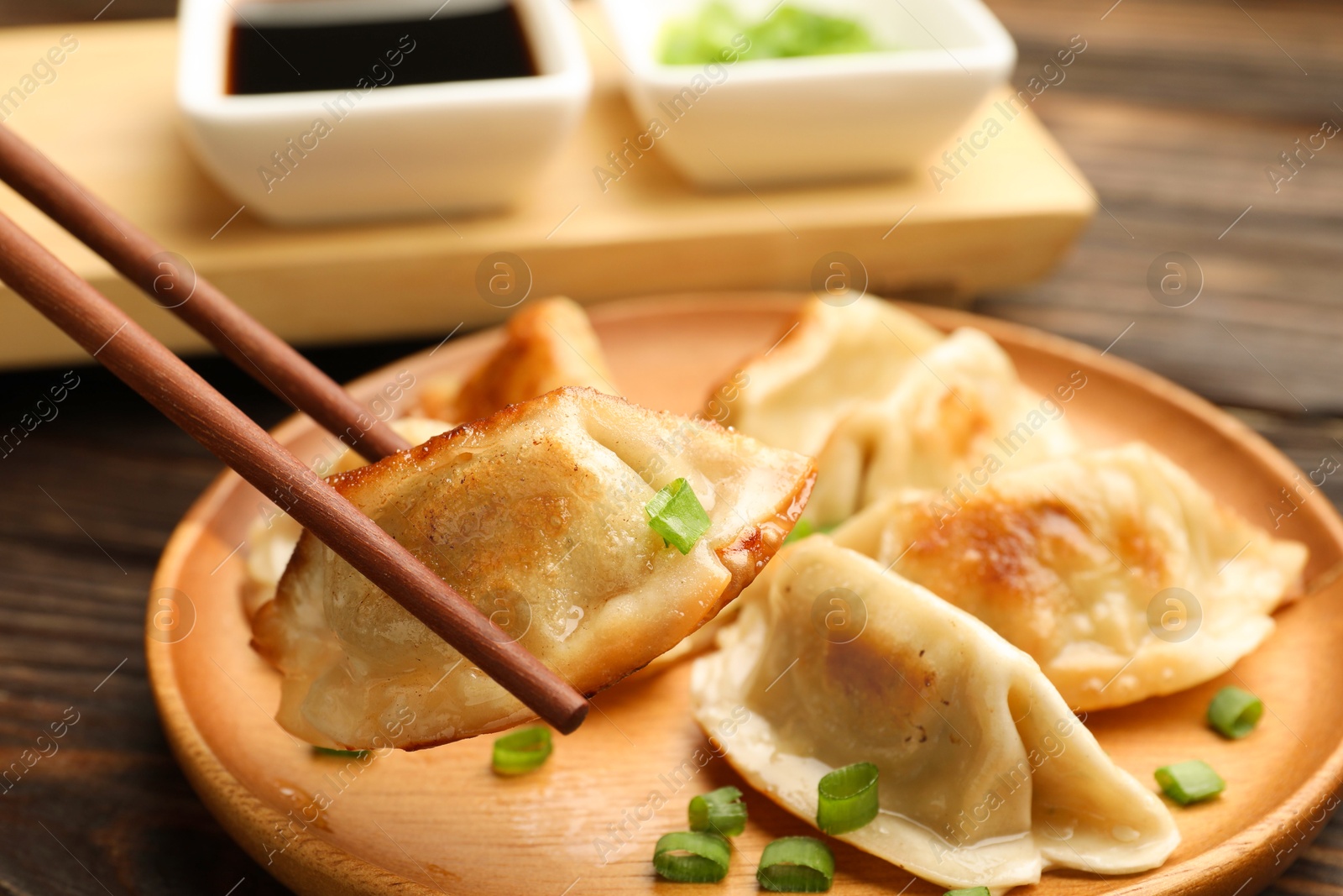 Photo of Eating fried gyoza dumplings at wooden table, closeup