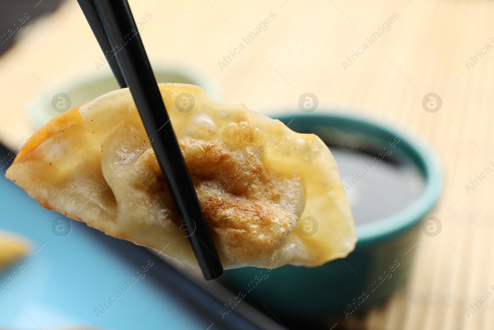 Photo of Eating fried gyoza dumpling at table, closeup