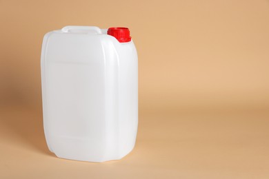 Photo of One white plastic canister on beige background, space for text