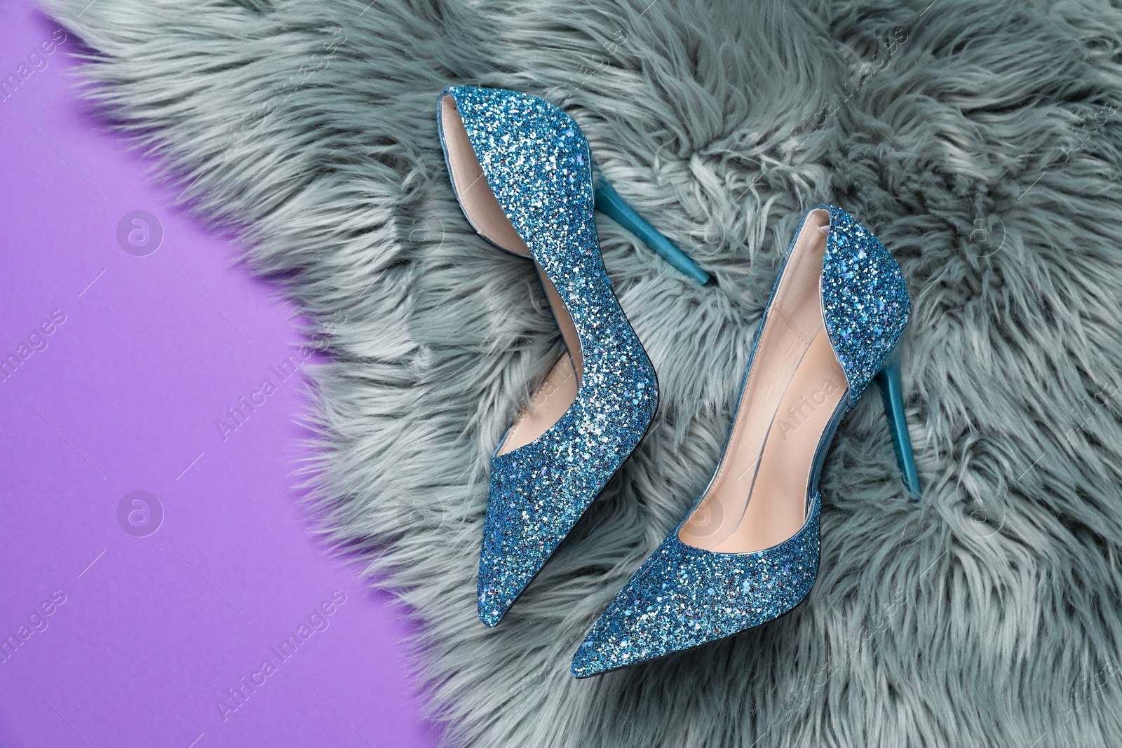 Photo of Beautiful high heeled shoes and faux fur on violet background, top view. Space for text