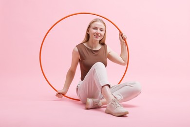 Photo of Beautiful young woman with hula hoop on pink background