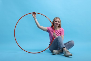 Photo of Beautiful young woman with hula hoop on light blue background