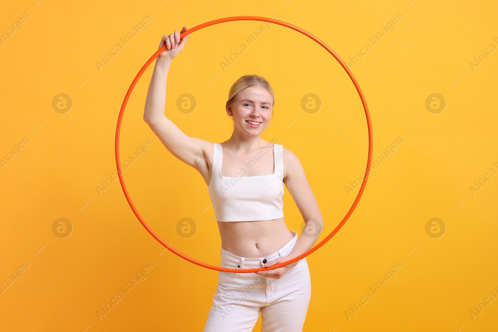 Photo of Beautiful young woman with hula hoop on yellow background