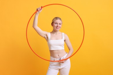 Photo of Beautiful young woman with hula hoop on yellow background