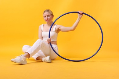 Photo of Beautiful young woman with hula hoop on yellow background