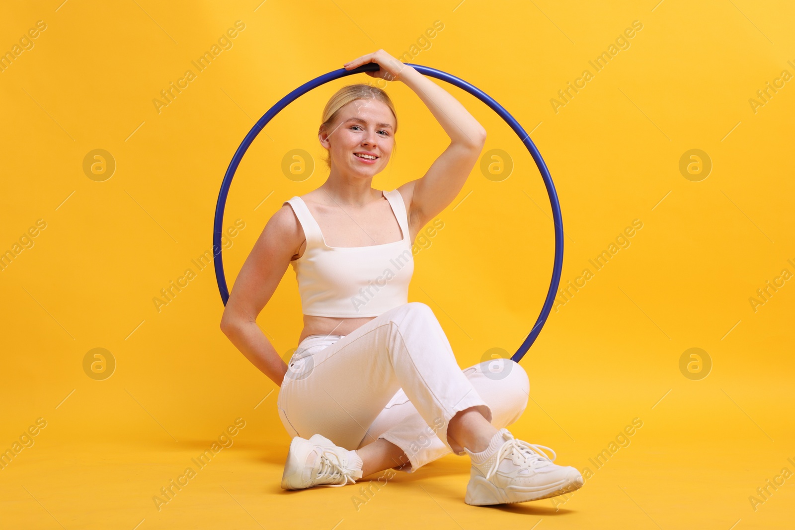 Photo of Beautiful young woman with hula hoop on yellow background