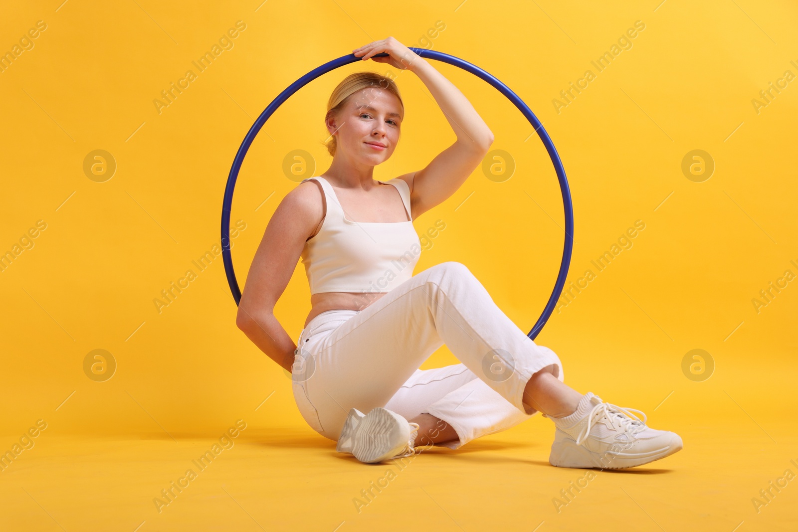 Photo of Beautiful young woman with hula hoop on yellow background