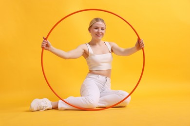 Photo of Beautiful young woman with hula hoop on yellow background