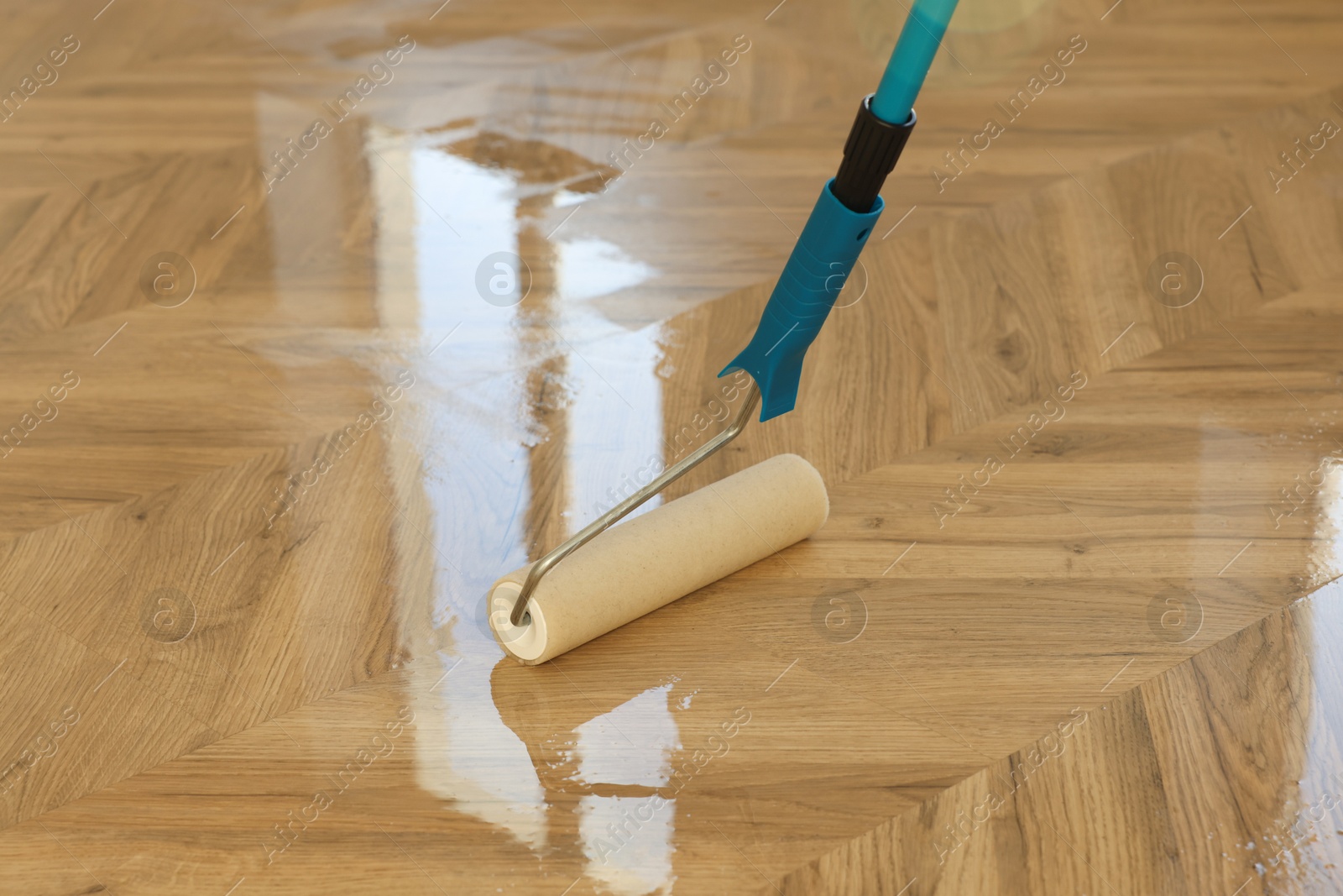 Photo of Polishing parquet with roller and varnish indoors, closeup