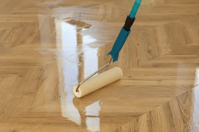 Photo of Polishing parquet with roller and varnish indoors, closeup