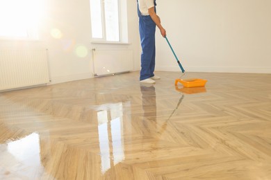 Photo of Process of polishing. Man dipping roller into tray with varnish indoors, closeup