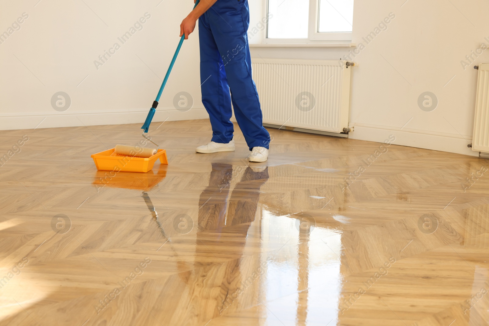 Photo of Process of polishing. Man dipping roller into tray with varnish indoors, closeup