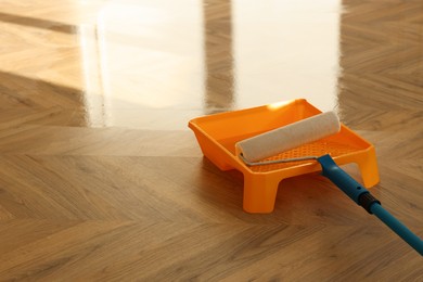 Photo of Process of polishing. Roller and tray with varnish on floor, space for text