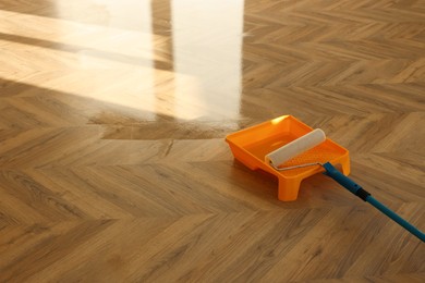 Photo of Process of polishing. Roller and tray with varnish on floor, space for text