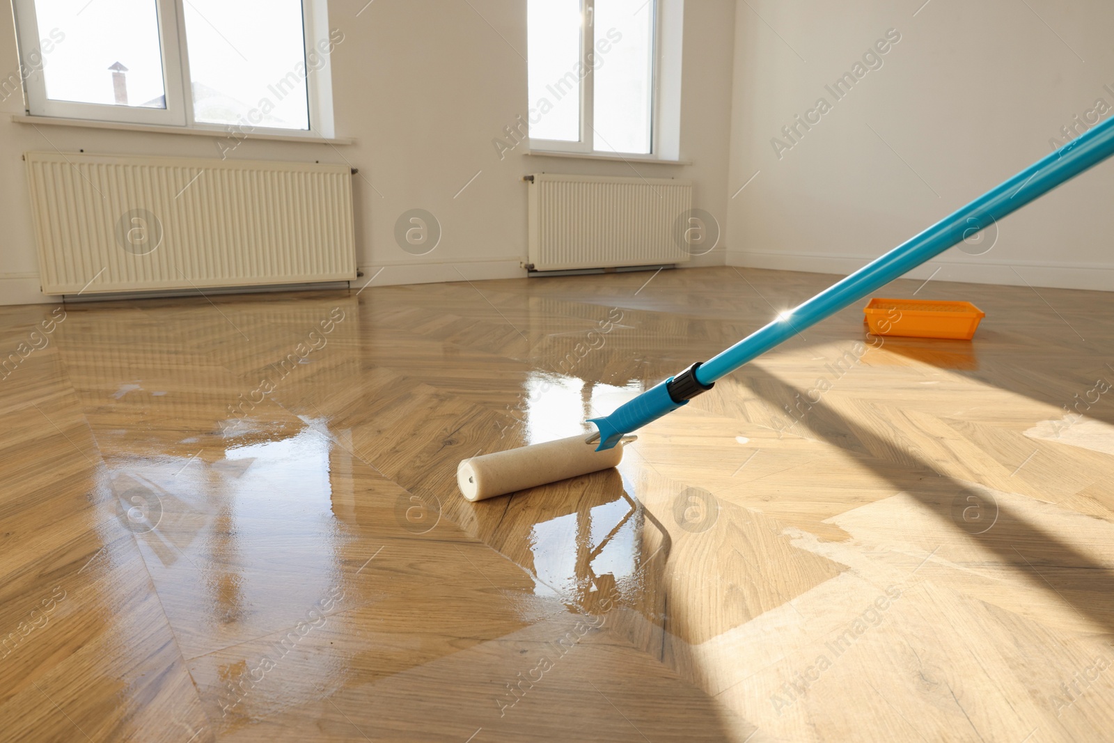 Photo of Polishing parquet with roller and varnish indoors, closeup