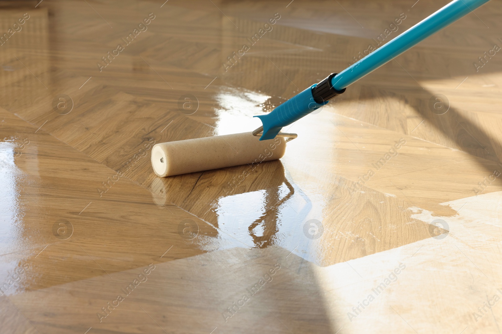 Photo of Polishing parquet with roller and varnish indoors, closeup