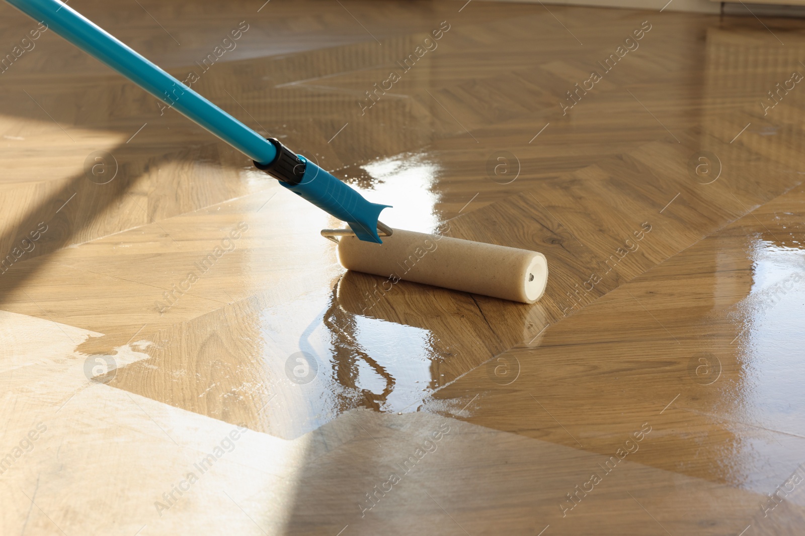 Photo of Polishing parquet with roller and varnish indoors, closeup