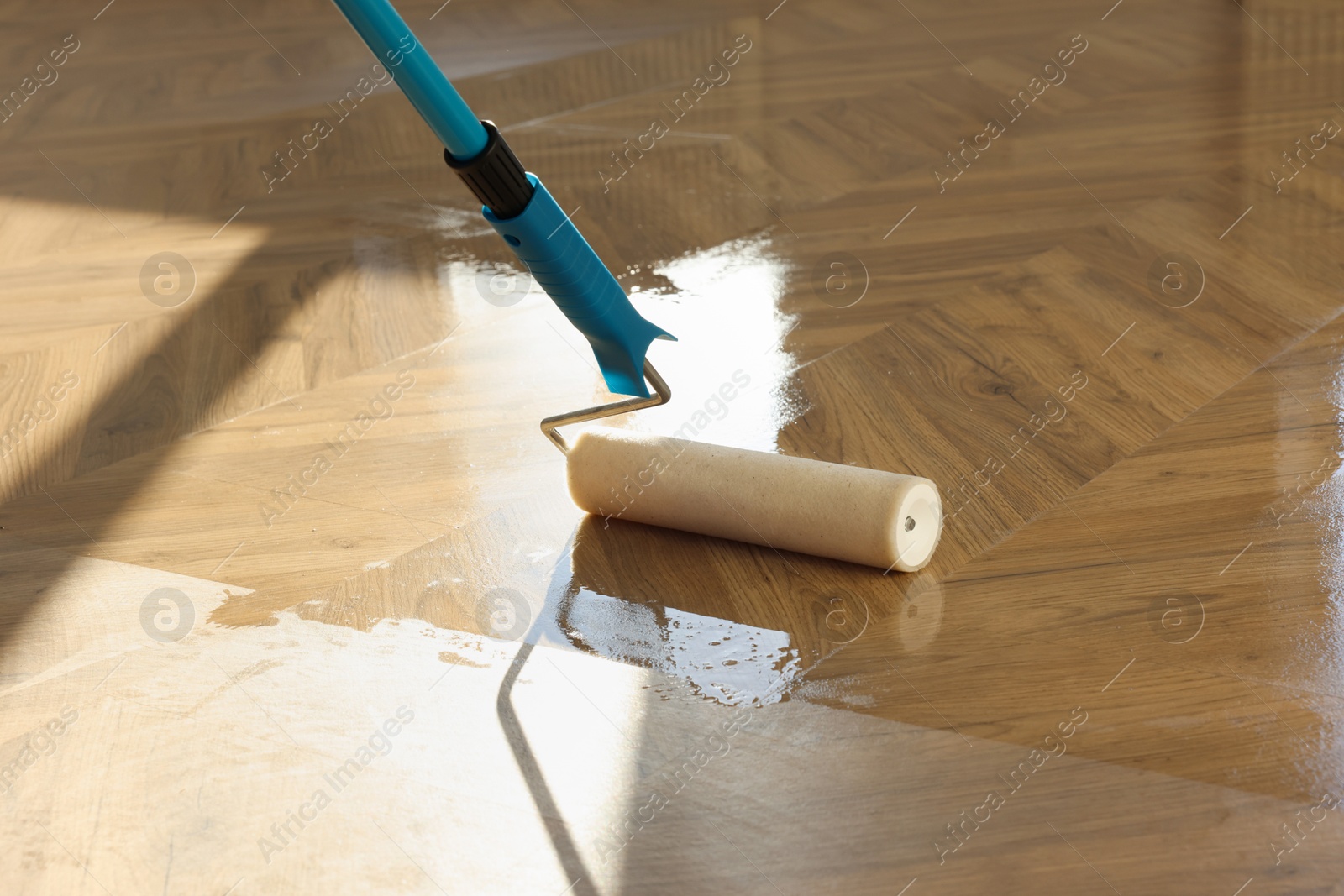 Photo of Polishing parquet with roller and varnish indoors, closeup