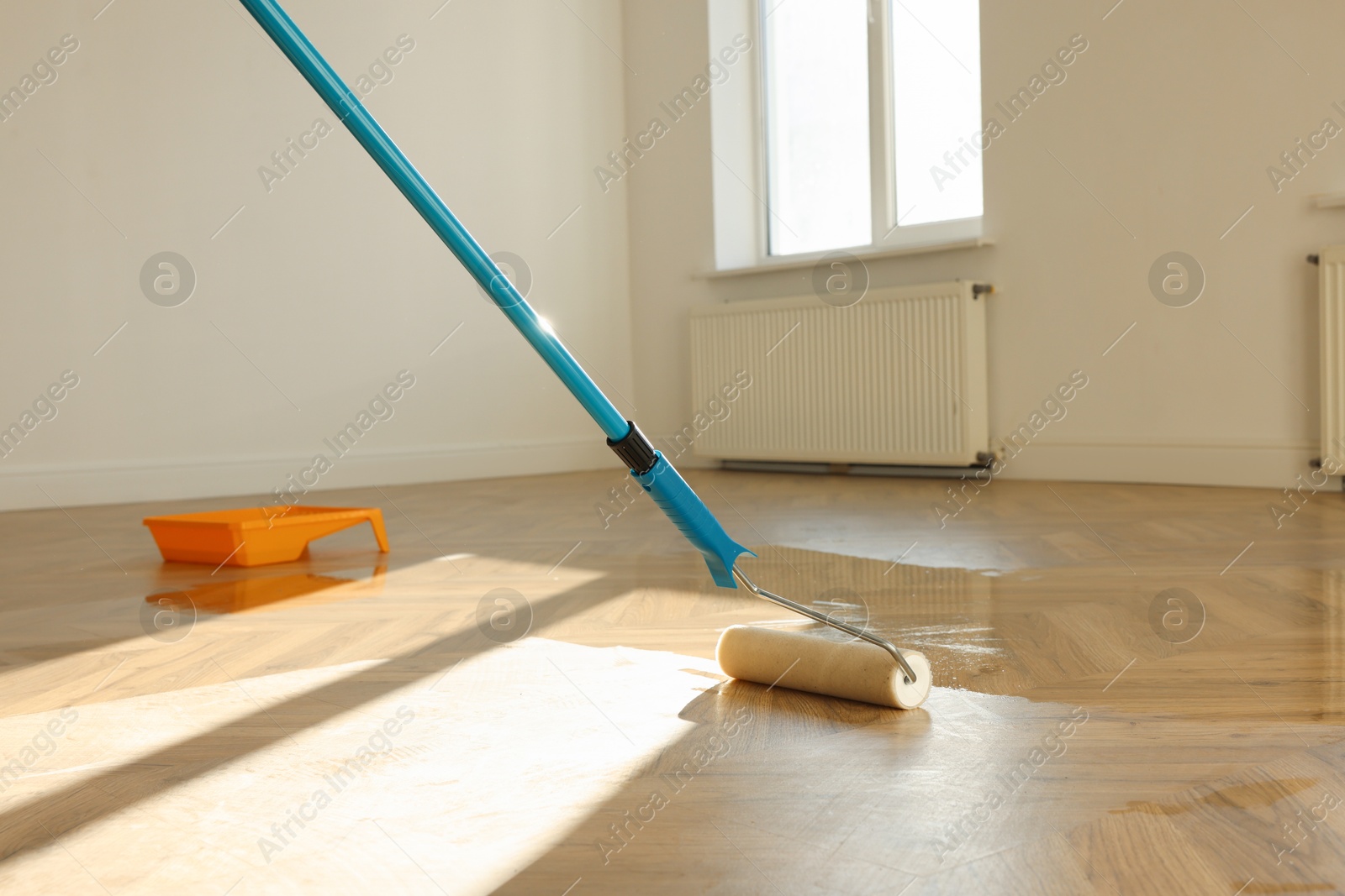 Photo of Polishing parquet with roller and varnish indoors, closeup