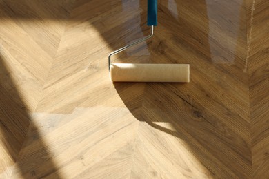 Photo of Polishing parquet with roller and varnish indoors, closeup. Space for text