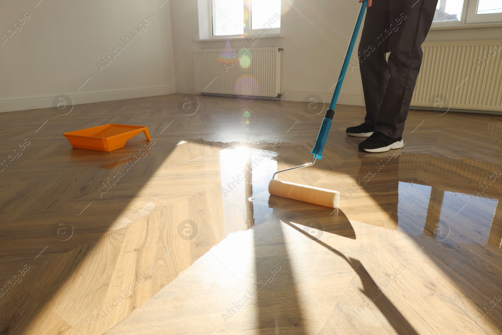 Photo of Man polishing parquet with varnish indoors, closeup