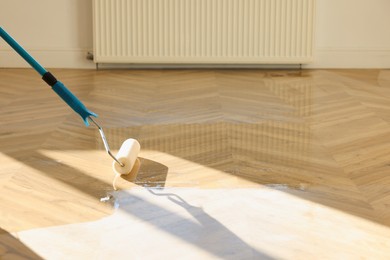 Photo of Polishing parquet with roller and varnish indoors, closeup. Space for text