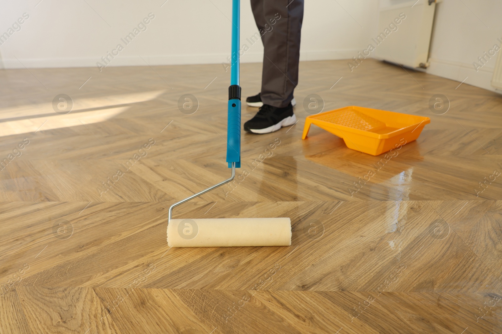 Photo of Man polishing parquet with varnish indoors, closeup