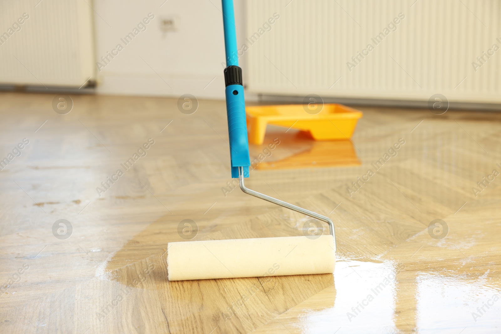 Photo of Polishing parquet with roller and varnish indoors, closeup