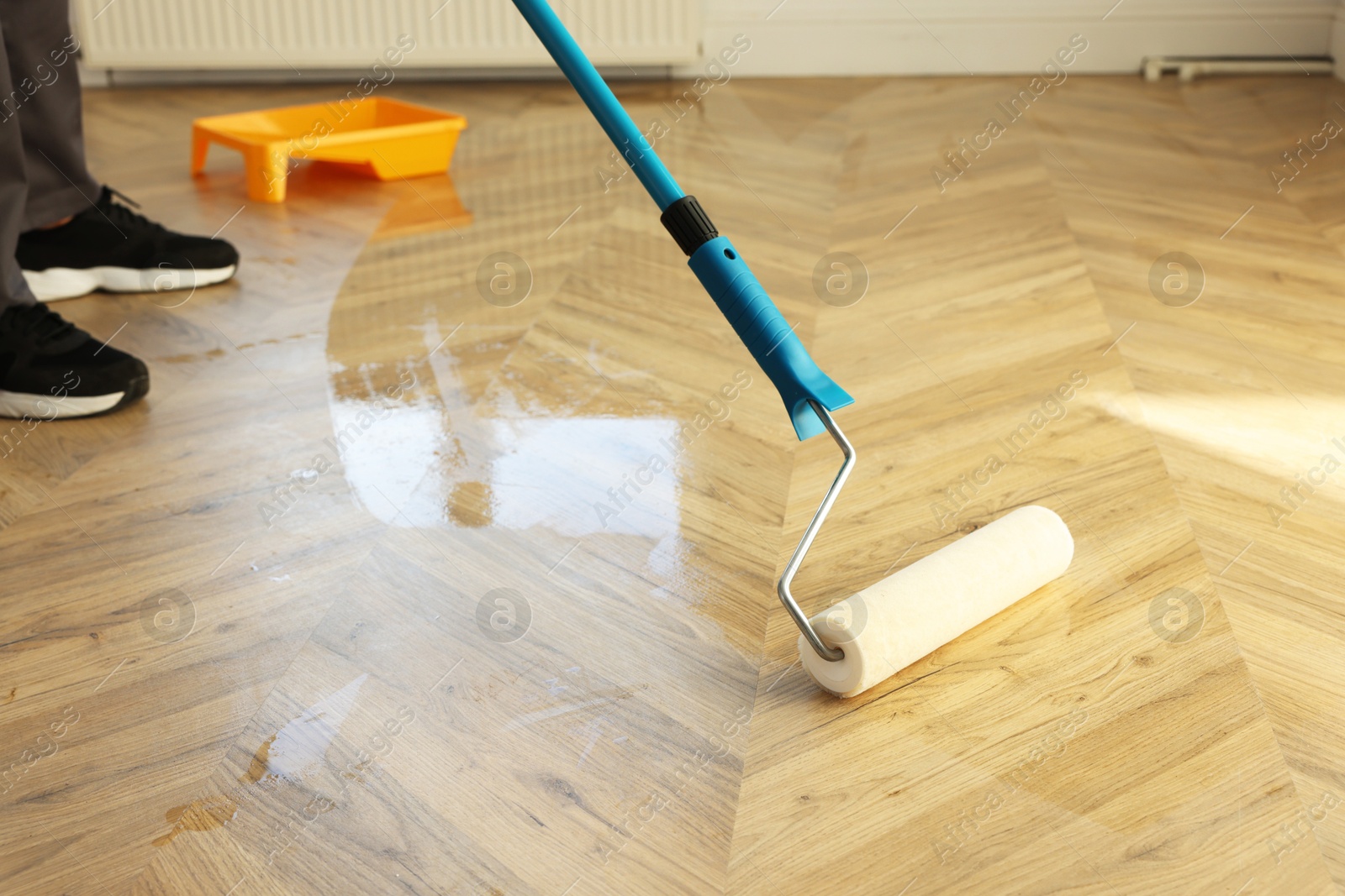 Photo of Man polishing parquet with varnish indoors, closeup