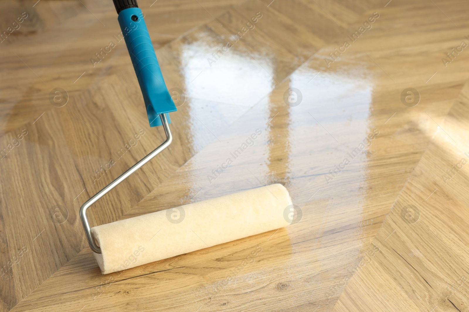 Photo of Polishing parquet with roller and varnish indoors, closeup. Space for text