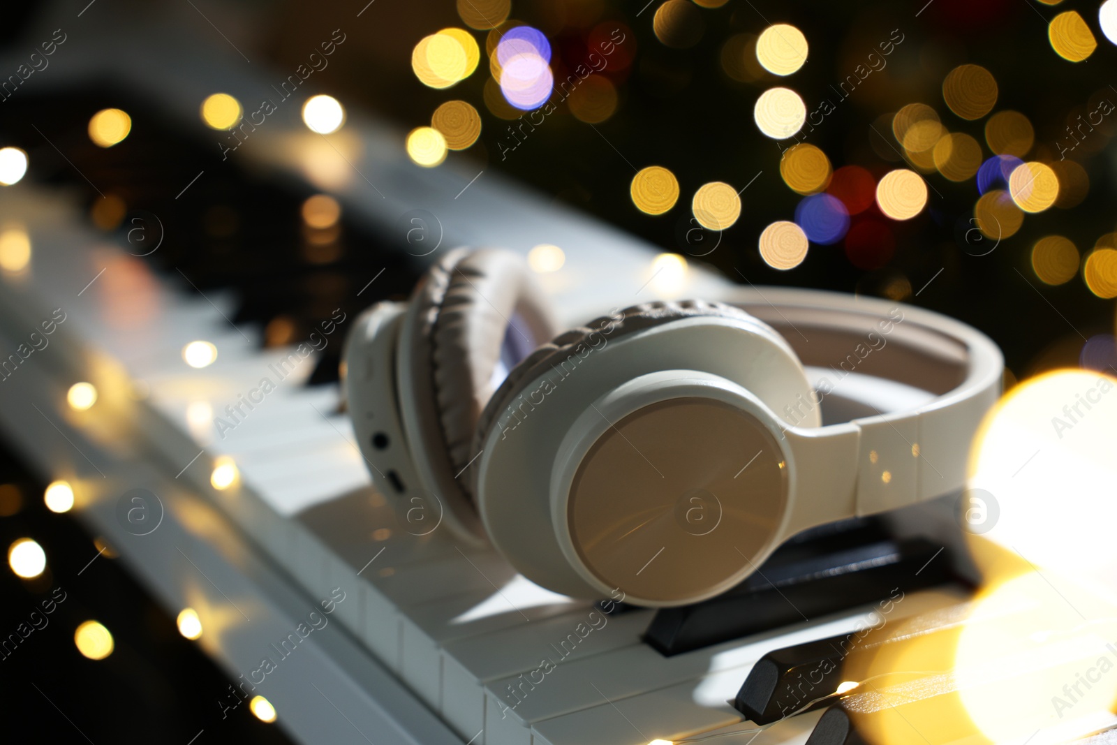 Headphones on electric piano against blurred lights, closeup. Bokeh effect Photo of Headphones on electric piano against blurred lights, closeup. Bokeh effect