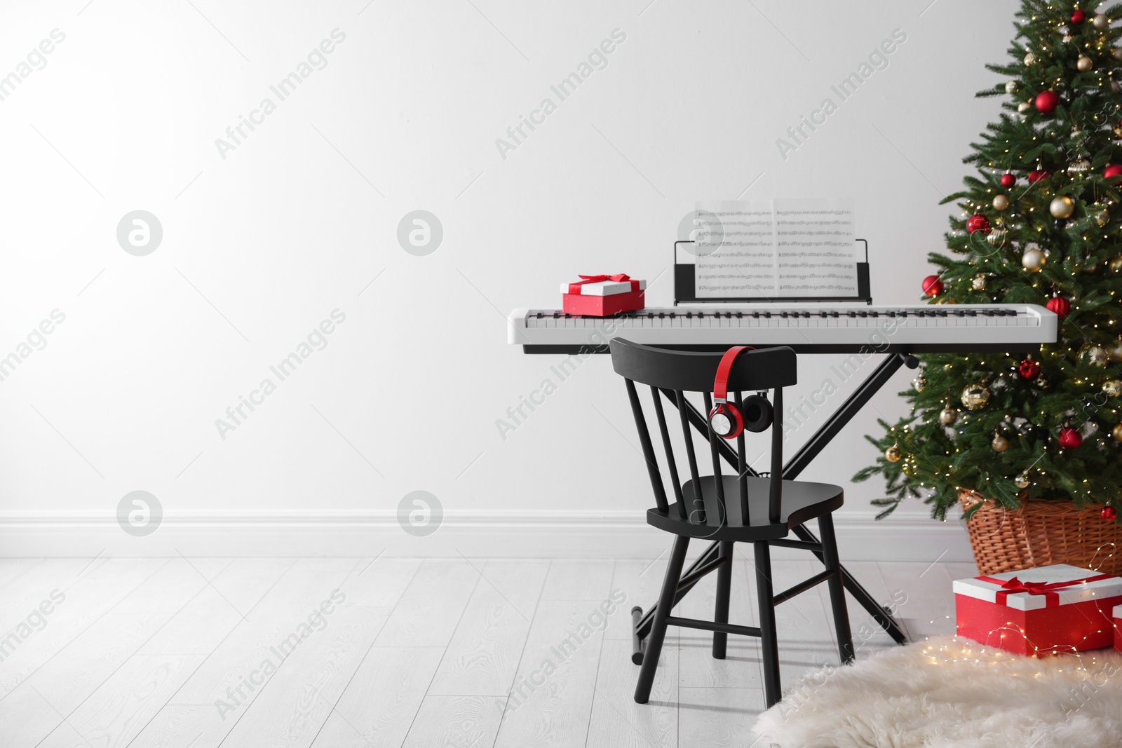 Synthesizer with music sheets and gift boxes near Christmas tree indoors, space for text Photo of Synthesizer with music sheets and gift boxes near Christmas tree indoors, space for text