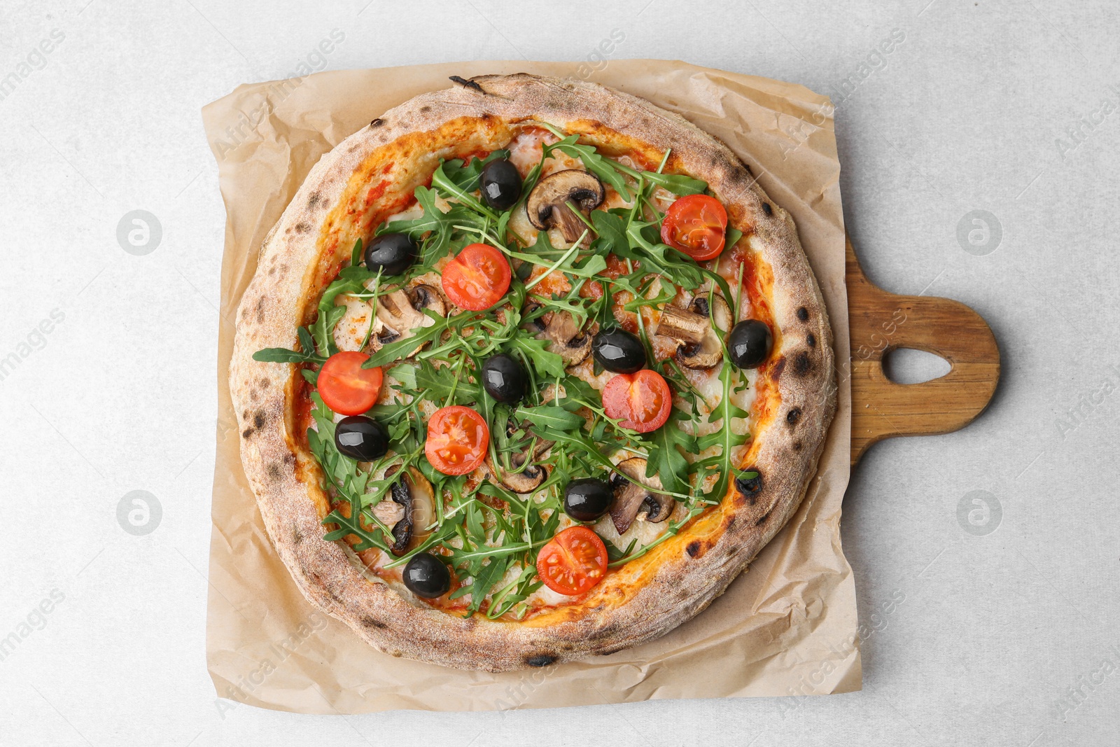 Tasty pizza with cherry tomatoes, black olives, mushrooms and arugula on light grey table, top view Photo of Tasty pizza with cherry tomatoes, black olives, mushrooms and arugula on light grey table, top view