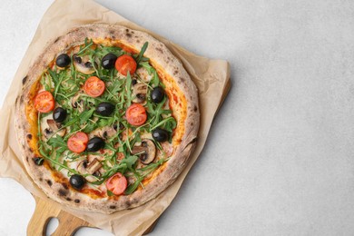 Photo of Tasty pizza with cherry tomatoes, black olives, mushrooms and arugula on light grey table, top view. Space for text