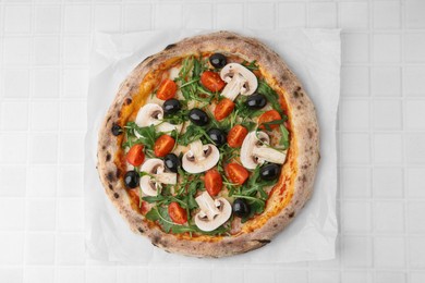 Photo of Tasty pizza with cherry tomatoes, black olives, mushrooms and arugula on white tiled table, top view