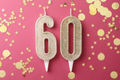 Photo of 60th birthday. Number shaped candles and confetti on pink background, flat lay