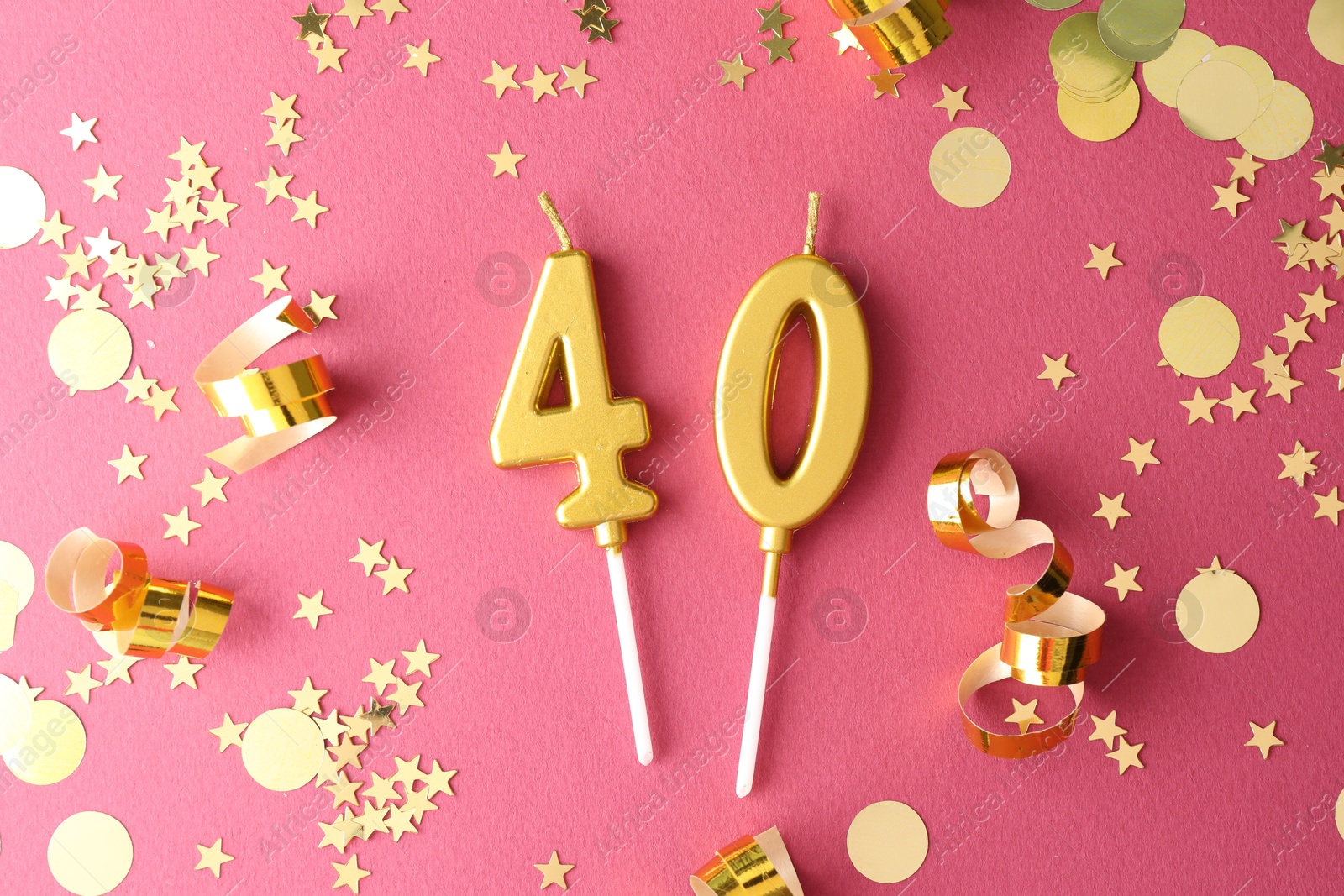 Photo of 40th birthday. Number shaped candles and confetti on pink background, flat lay