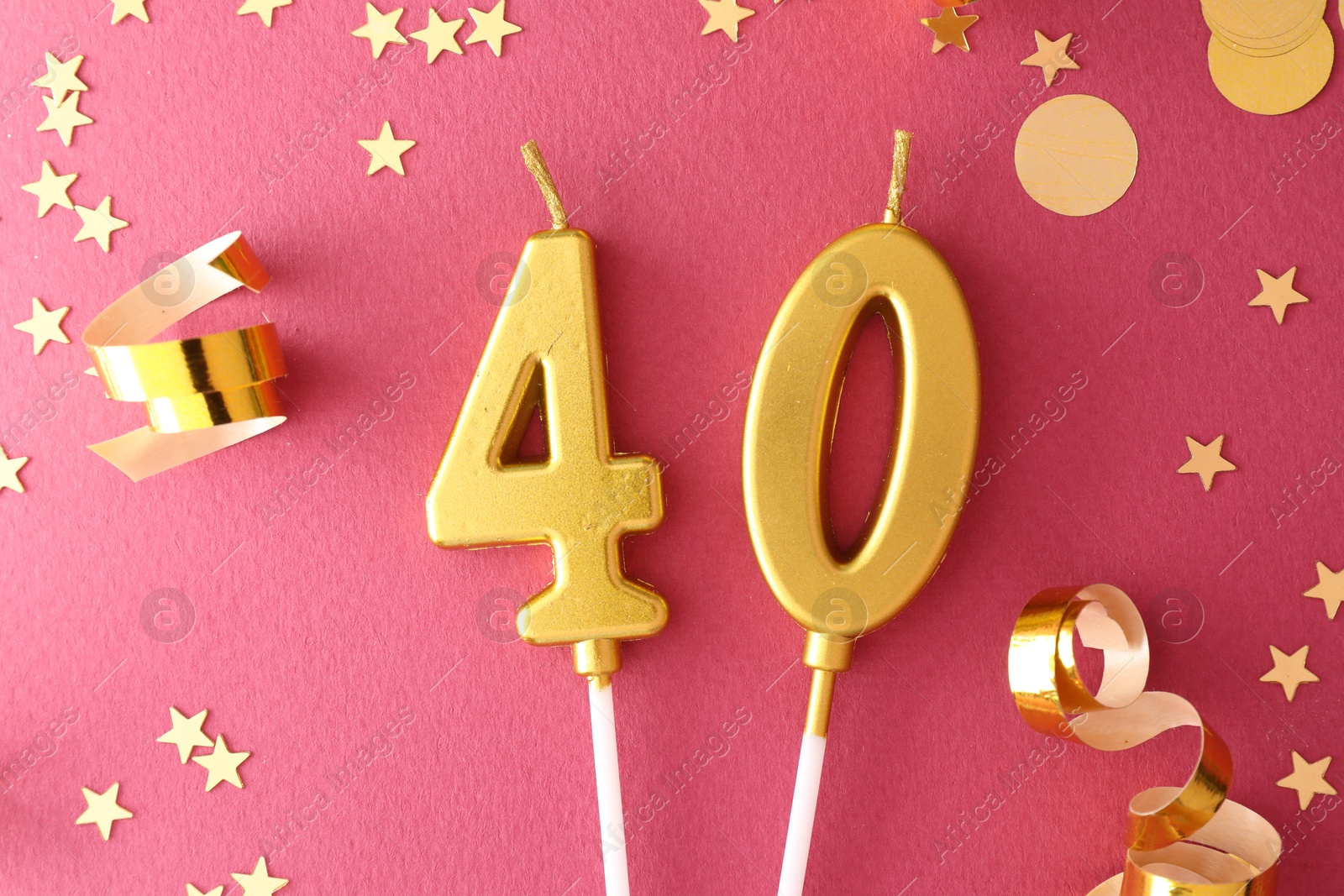 Photo of 40th birthday. Number shaped candles and confetti on pink background, flat lay