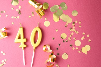 Photo of 40th birthday. Number shaped candles and confetti on pink background, flat lay