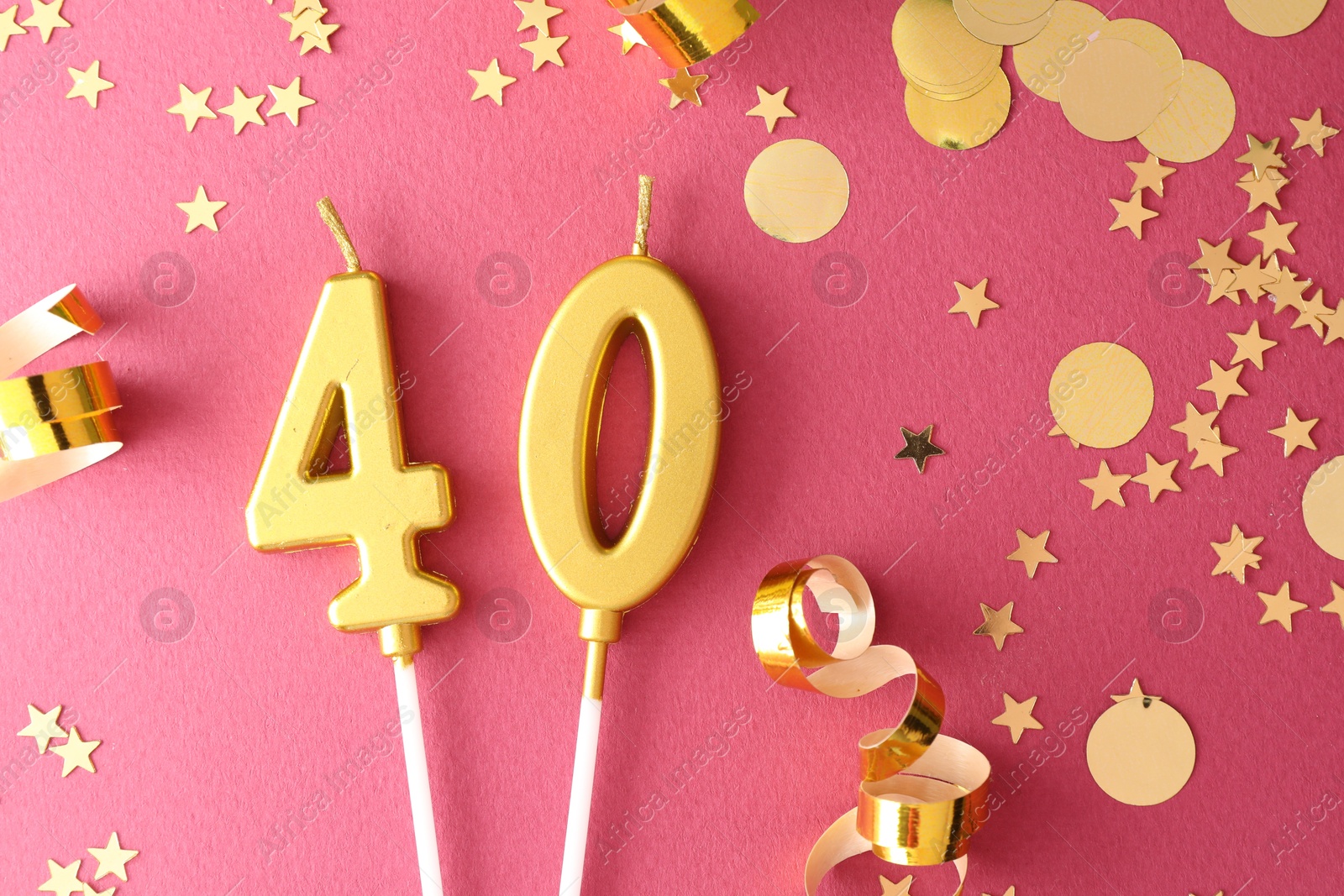 Photo of 40th birthday. Number shaped candles and confetti on pink background, flat lay