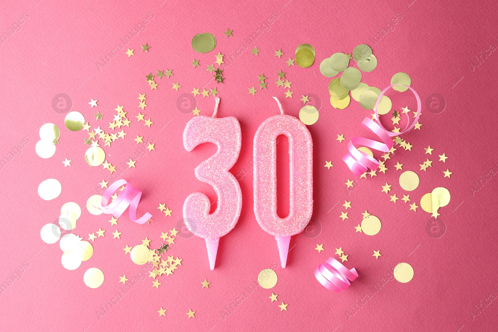 Photo of 30th birthday. Number shaped candles and confetti on pink background, flat lay