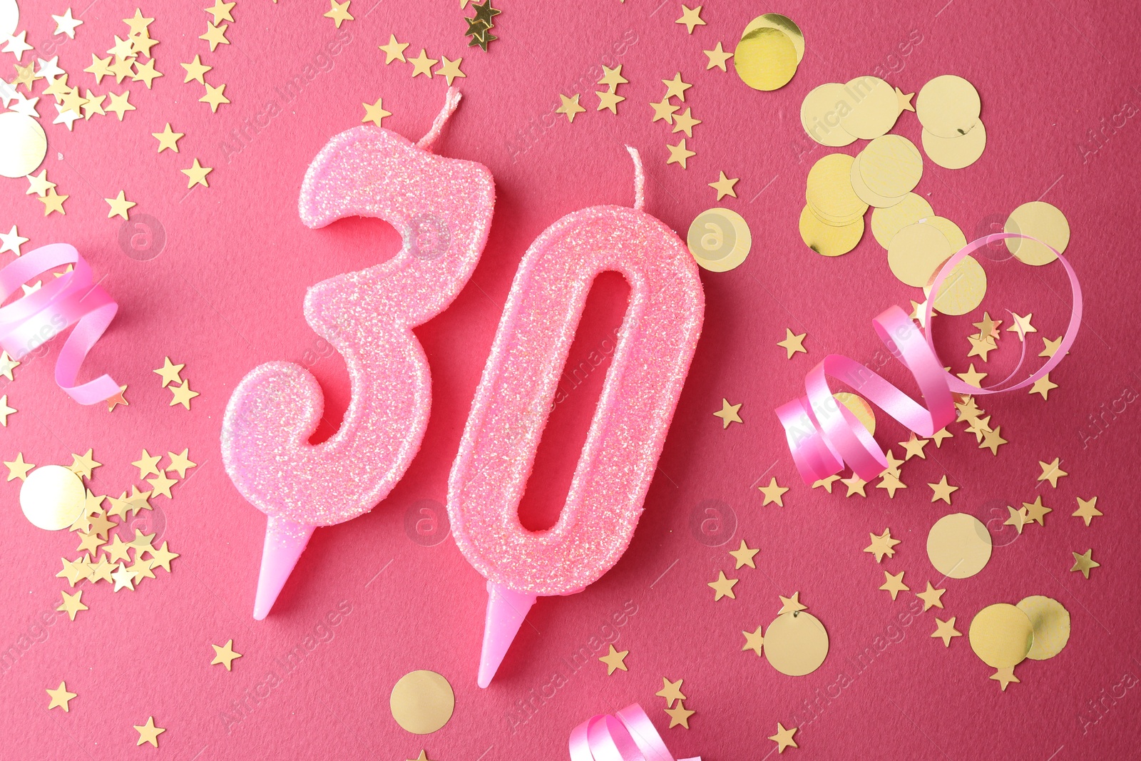 Photo of 30th birthday. Number shaped candles and confetti on pink background, flat lay