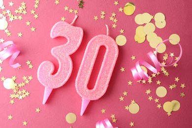 Photo of 30th birthday. Number shaped candles and confetti on pink background, flat lay