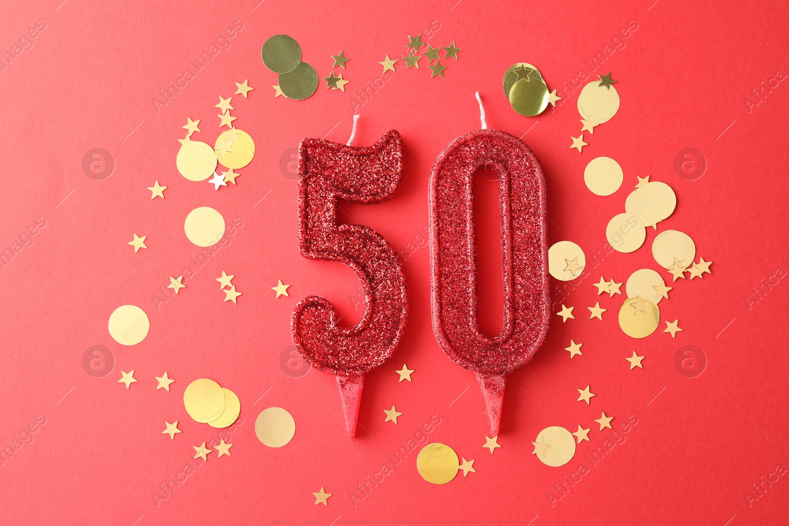 Photo of 50th birthday. Number shaped candles and confetti on red background, flat lay