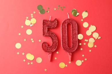 Photo of 50th birthday. Number shaped candles and confetti on red background, flat lay