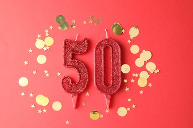 Photo of 50th birthday. Number shaped candles and confetti on red background, flat lay