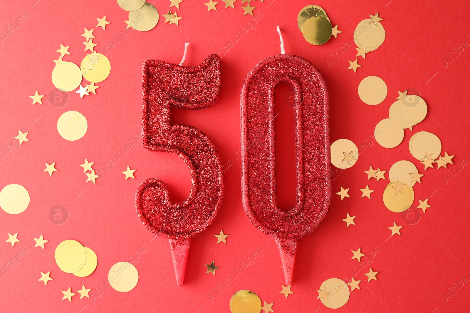 Photo of 50th birthday. Number shaped candles and confetti on red background, flat lay