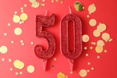 Photo of 50th birthday. Number shaped candles and confetti on red background, flat lay