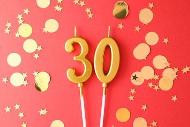 Photo of 30th birthday. Number shaped candles and confetti on red background, flat lay