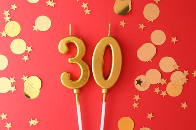 Photo of 30th birthday. Number shaped candles and confetti on red background, flat lay